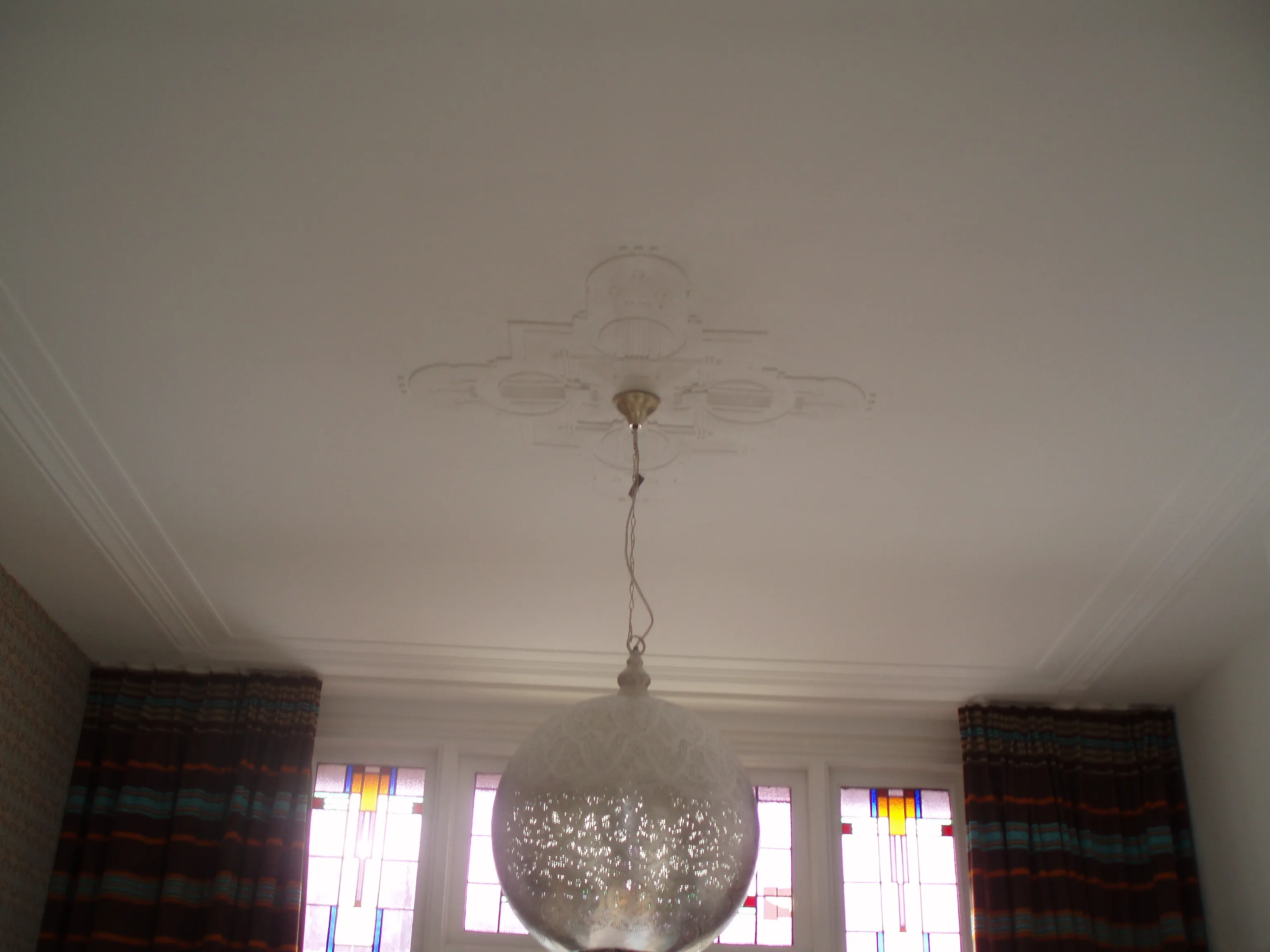 Gerestaureerd plafond met sierornament en originele glas-in-loodramen