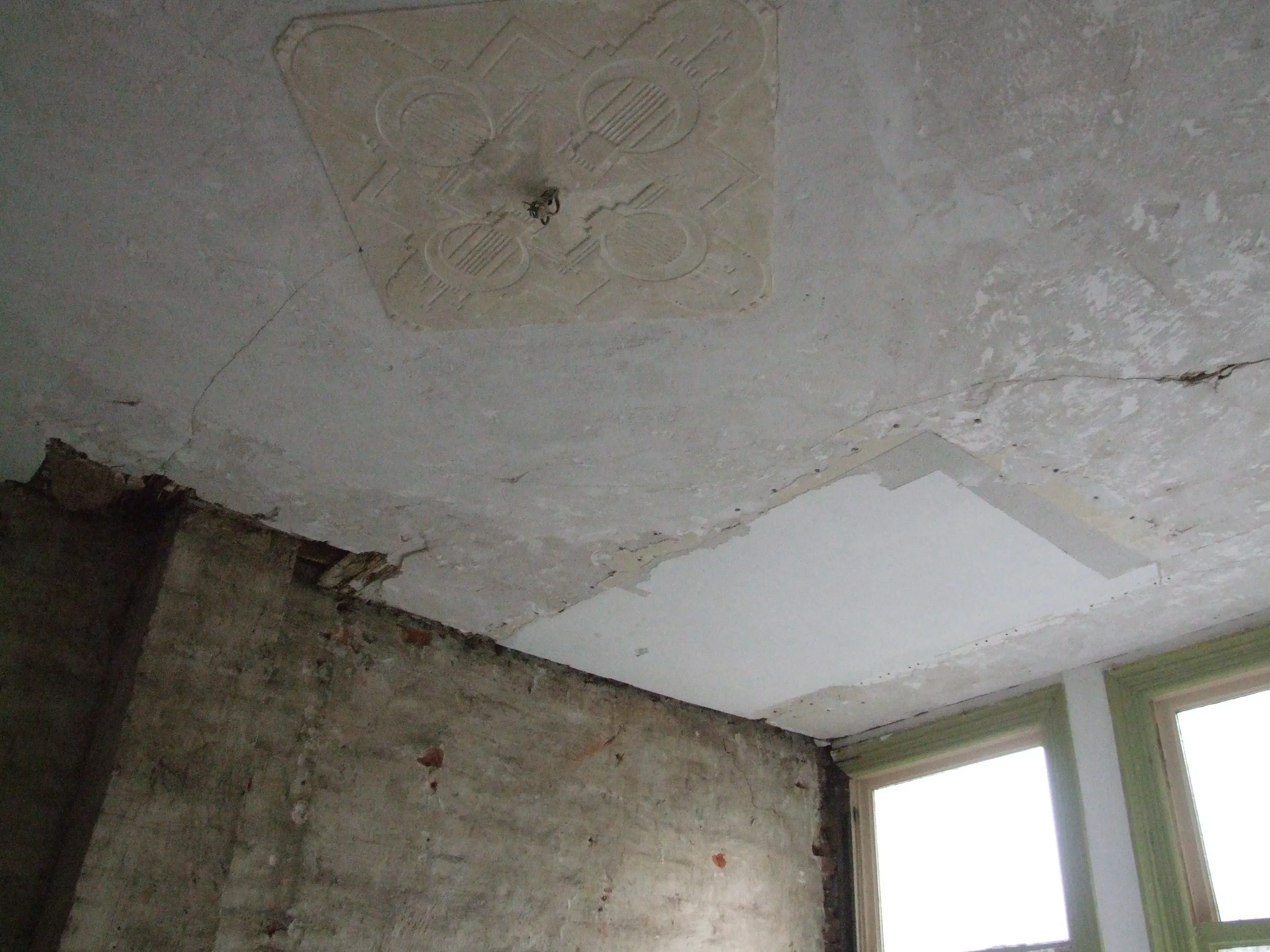 Beschadigd origineel plafond met ornament vóór restauratie