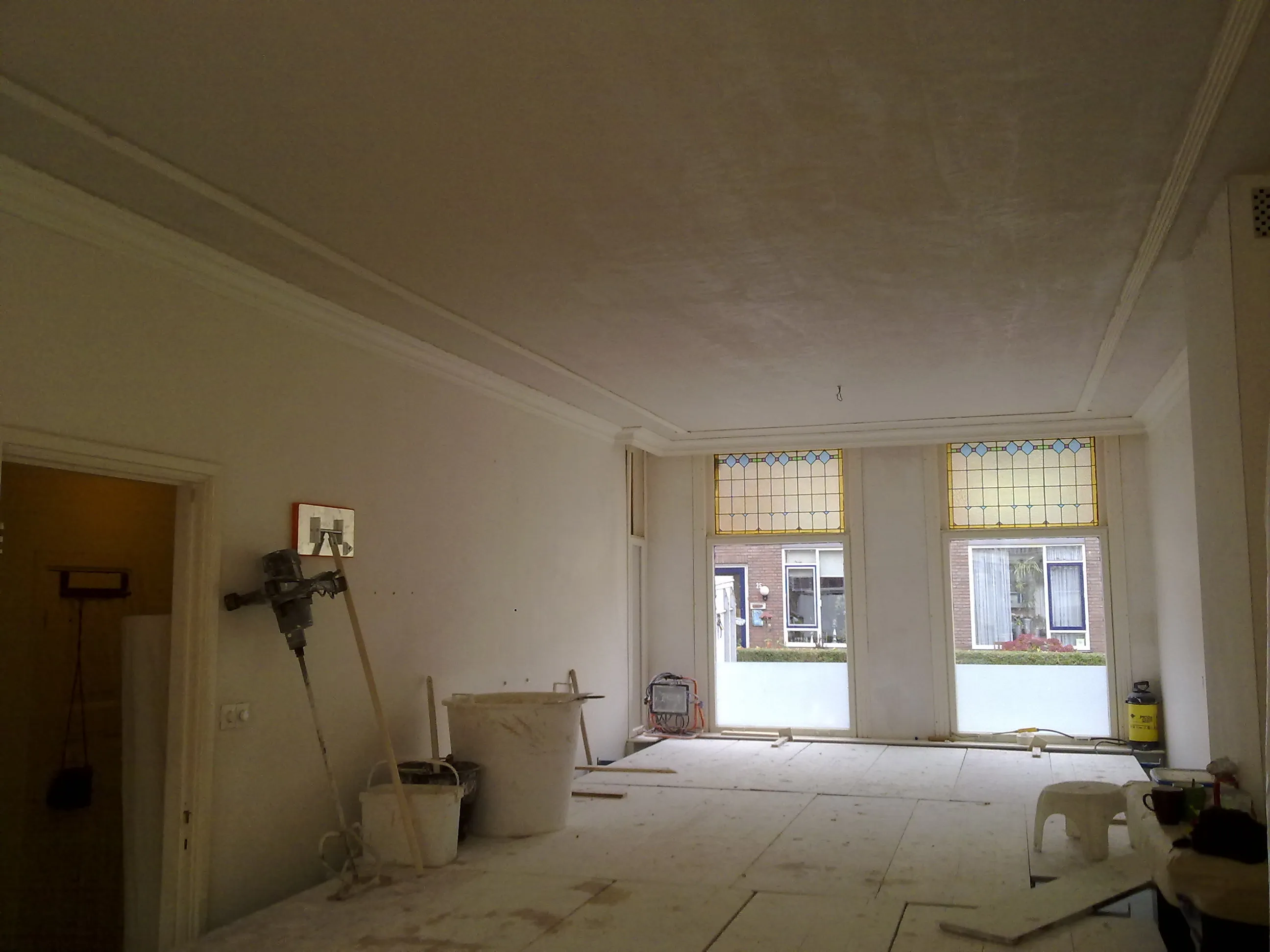 Glad gestukadoorde woonkamer met plafondlijsten en glas-in-loodramen